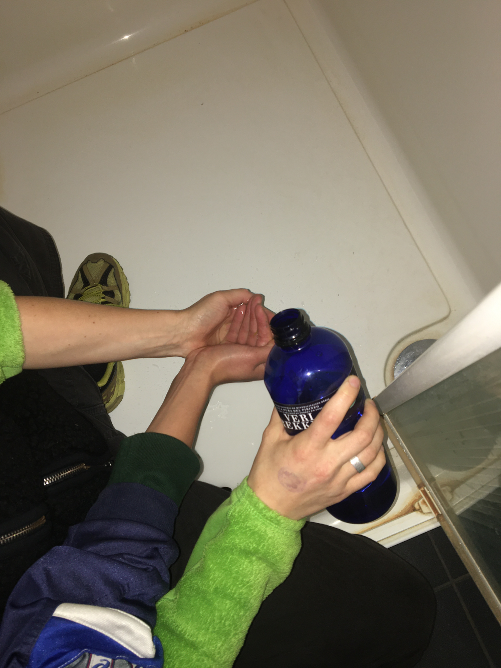 Two people cupping their hands together while one holds a bottle over them