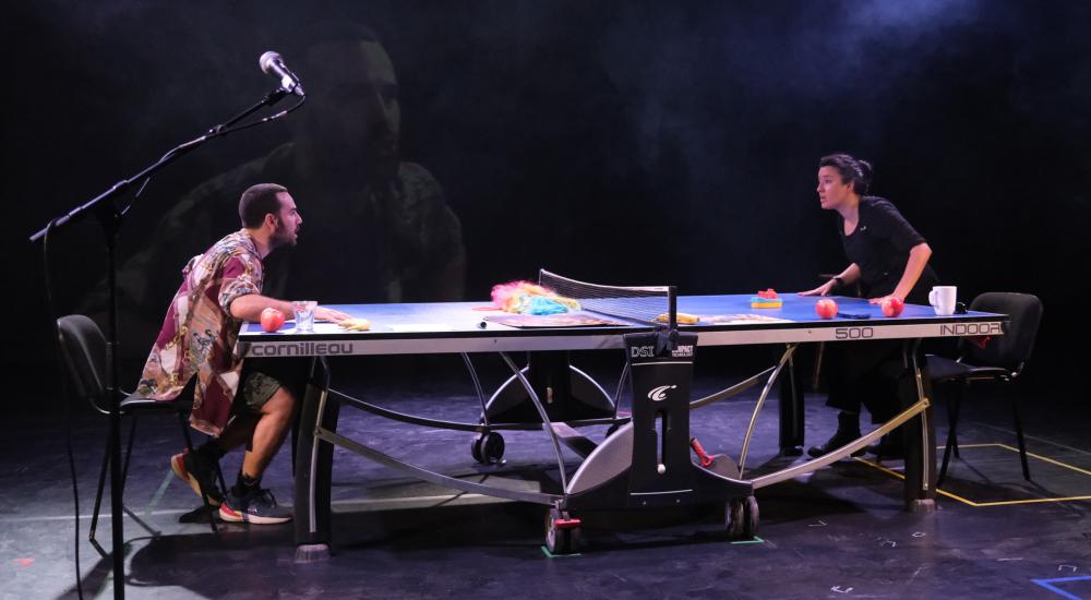 Two people leaning on a ping pong table 