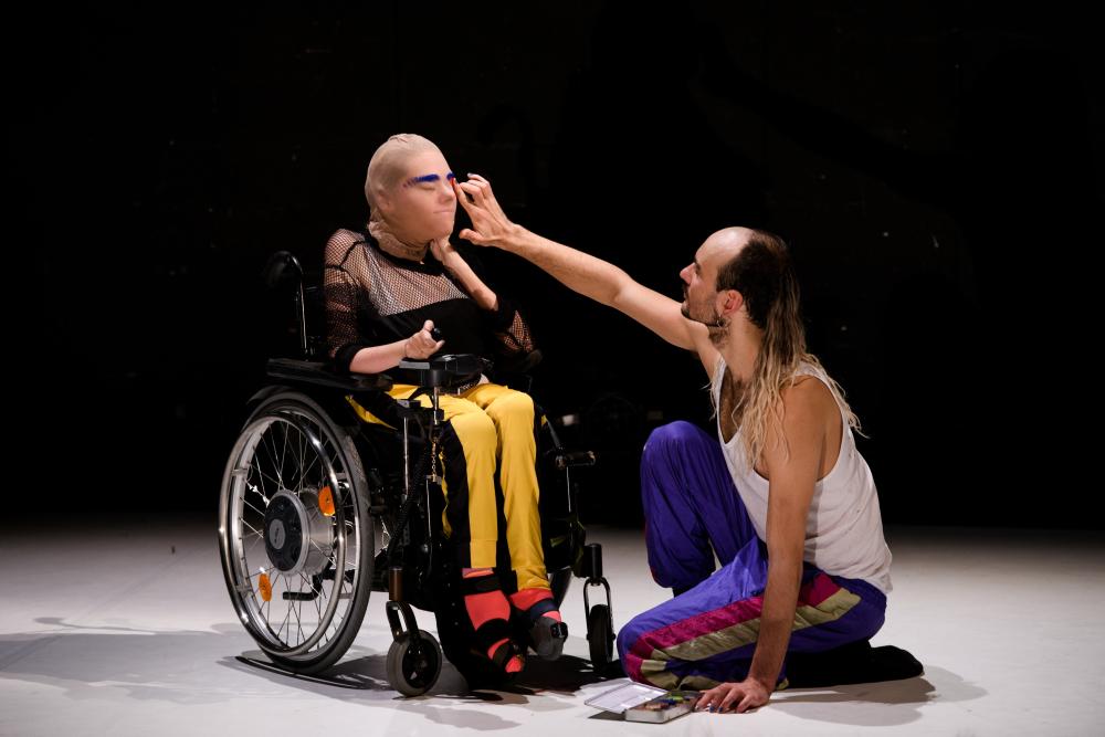 persoon met een masker in een rolstoel aangeraakt door een andere persoon