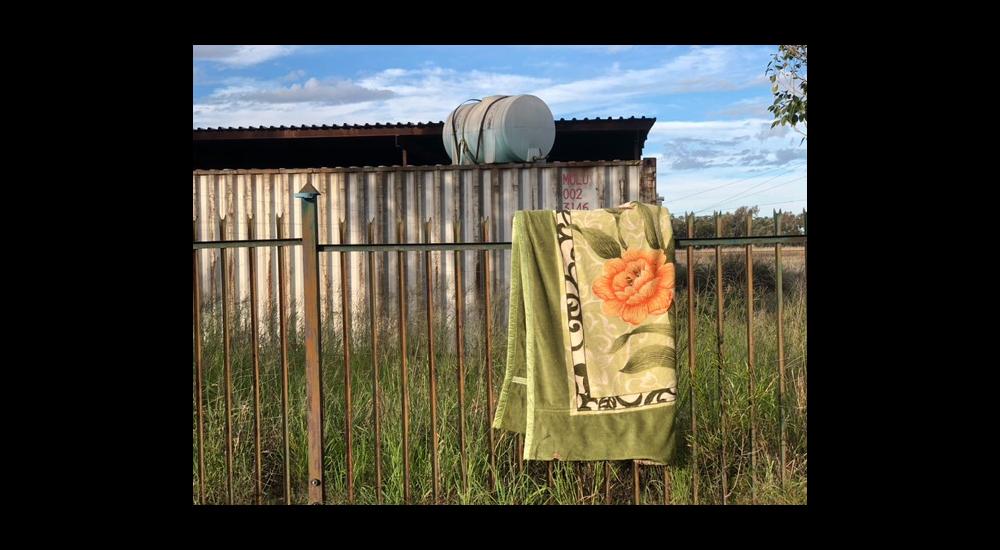 A blanket with a flower on it folded over a fence