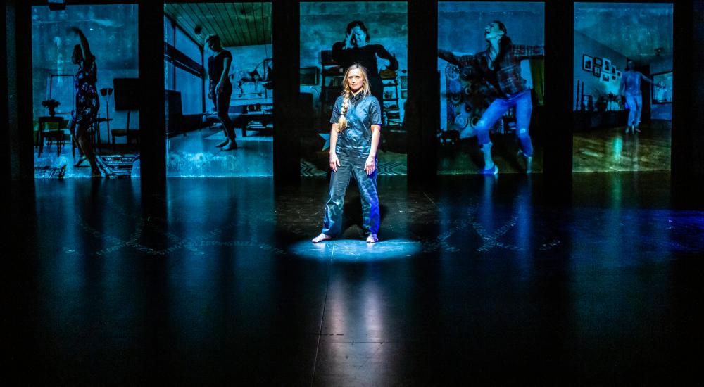 Person standing in front of blue projections on a stage