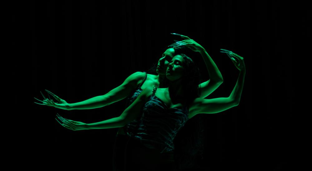two dancers in green light with long nails