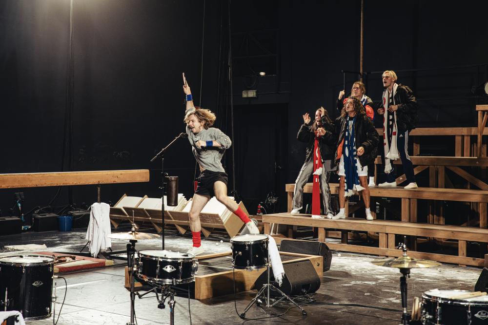 A performer jumping on a springboard while singing into a microphone