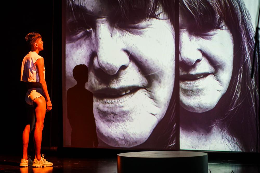 Person standing on stage and in front of photo