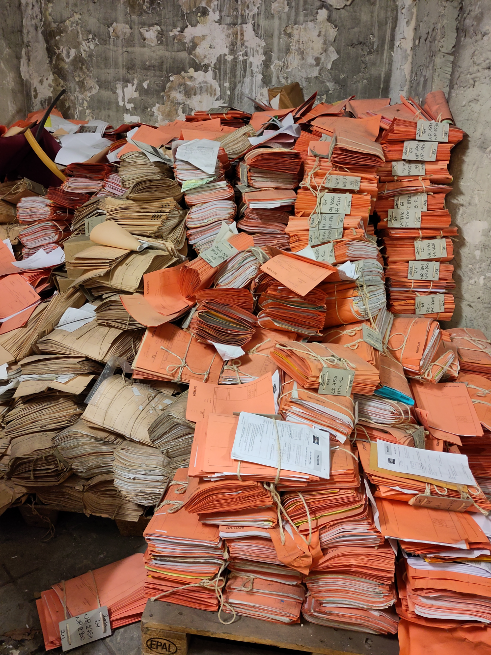A big stack of papers in orange binders at the Palace of Justice