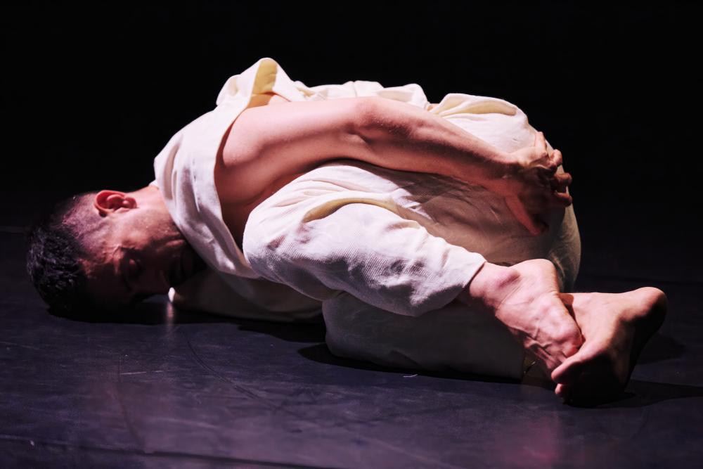 performer on the floor with their arms around their legs