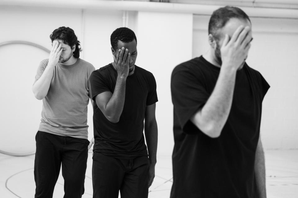 three dancers putting a hand to their faces