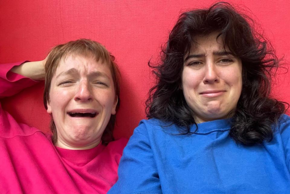 Two people crying in front of a red wall