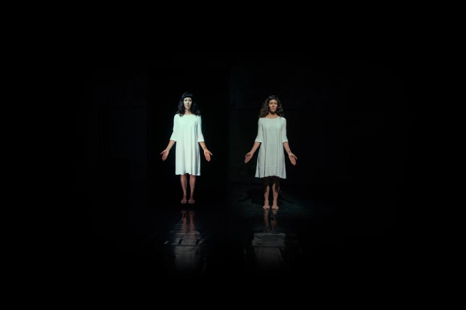 Two people in white dresses in a dark space