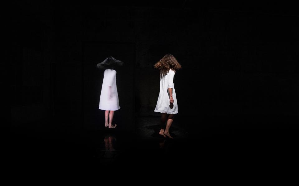 Two people in white dresses in a dark space