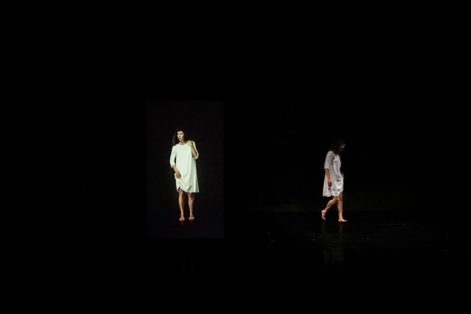 Two people in white dresses in a dark space
