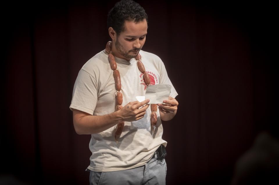 Anacarsis reading a piece of paper while wearing a necklace made of sausages