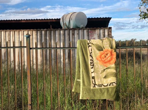 A blanket with a flower on it folded over a fence