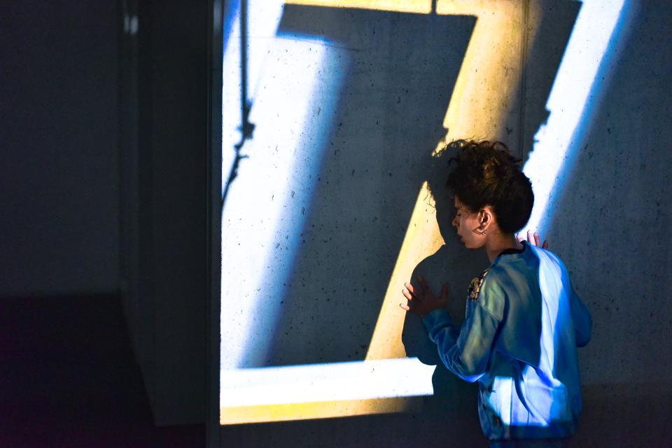 A woman turned towards a concrete wall