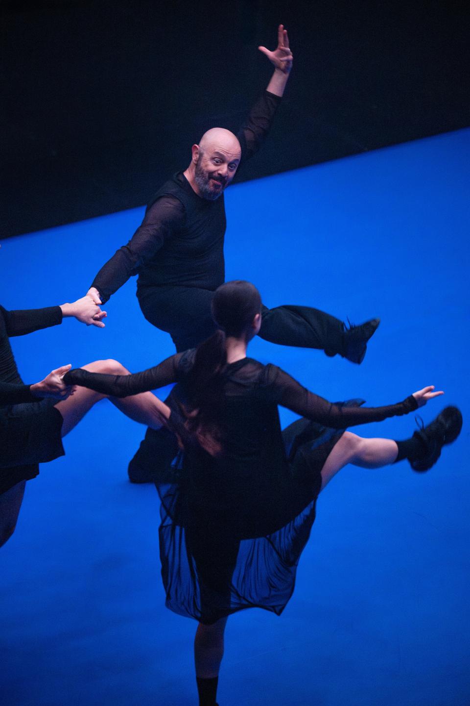3 performers with black clothes dancing on a bright blue floor