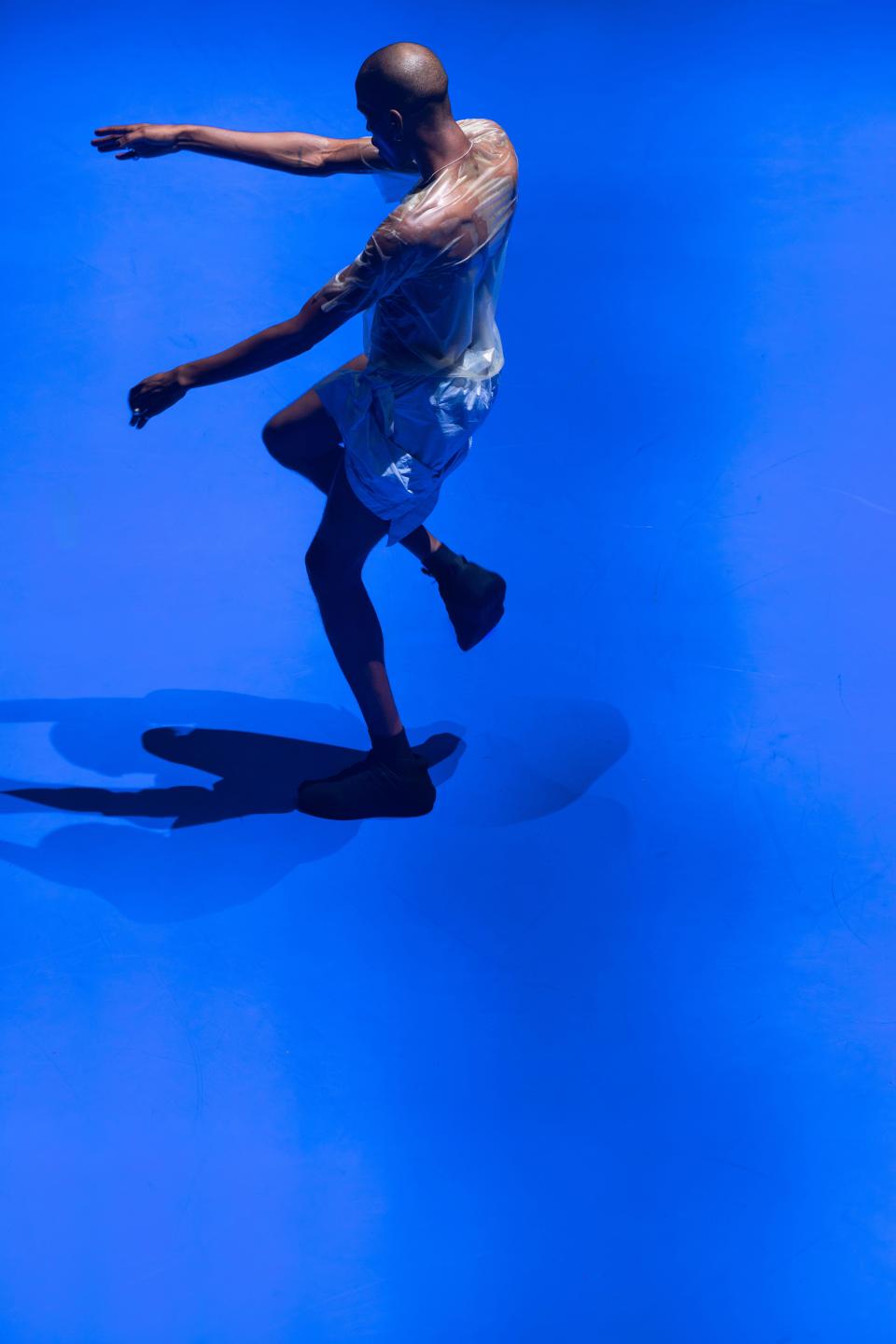 1 performers with black clothes dancing on a bright blue floor
